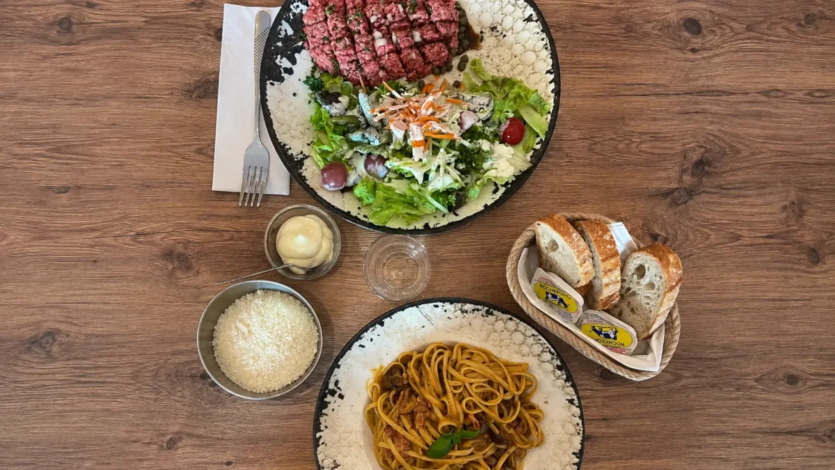 Filet américain, pâtes et pain sur une table en bois